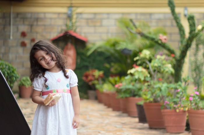 Niña comiendo sandwich y sonríendo