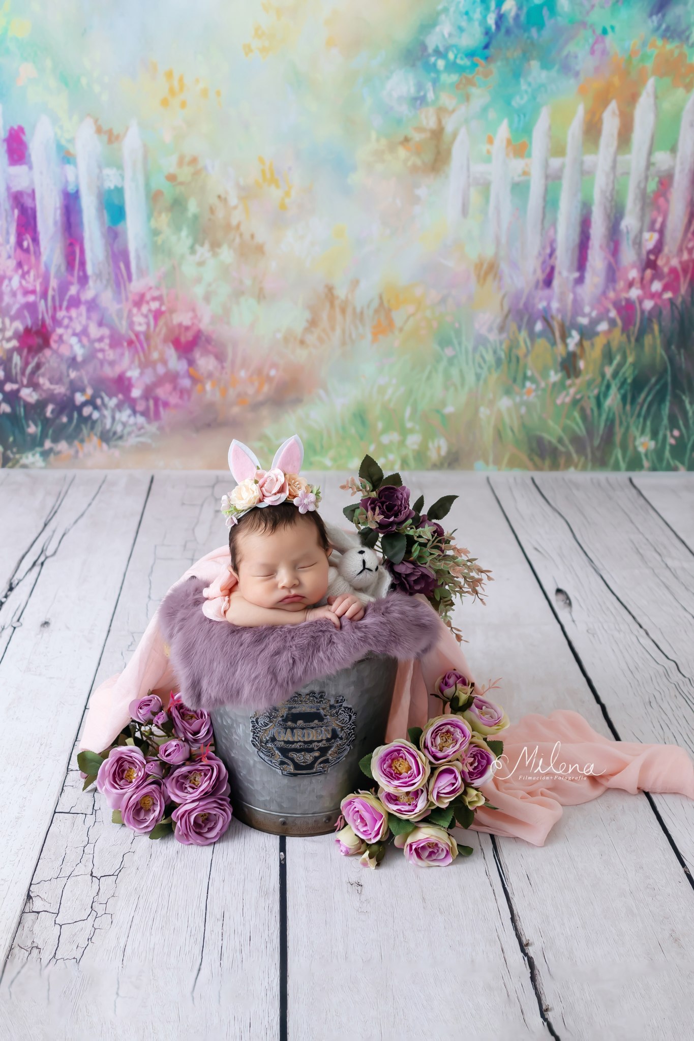 sesión newborn segura para niña en una cubeta con flores y orejas de conejo