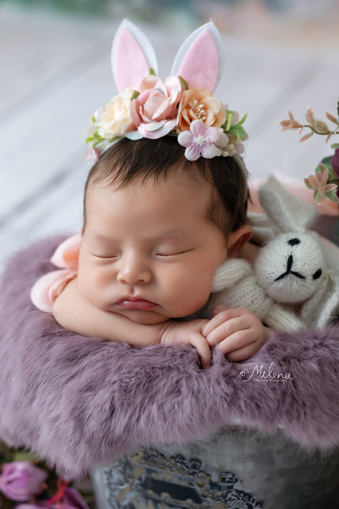 sesión newborn segura para niña en una cubeta con flores y orejas de conejo
